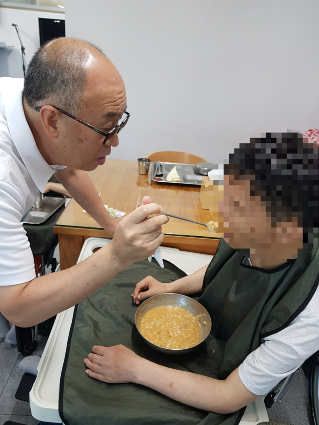 김무경(왼쪽) 씨가 스스로 밥 먹기가 힘든 시설 입소 장애인의 식사를 돕고 있다. 김무경 씨 제공 
