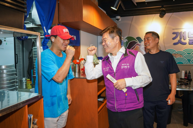 이필형(가운데) 서울 동대문구청장이 지역 상인을 격려하며 함께 파이팅을 외치고 있다. 동대문구청 제공