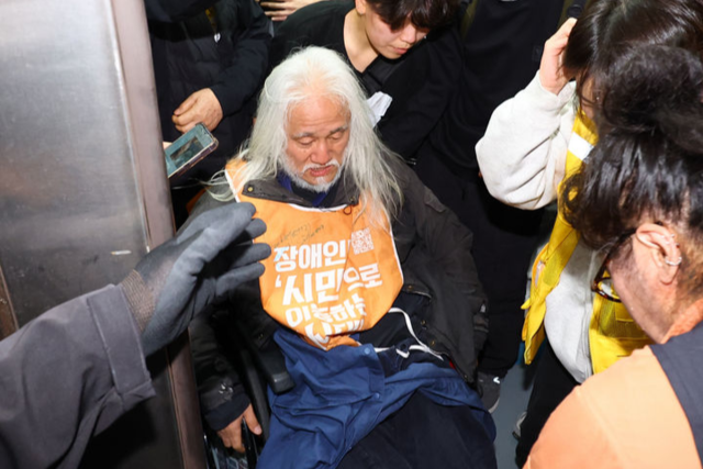 전국장애인차별철폐연대(전장연)의 출근길 지하철 탑승 시위가 1년여 만에 재개된 21일 서울 지하철 4호선 혜화역에서 전장연 회원이 지하철 탑승을 시도하다 서울교통공사 관계자와 충돌하고 있다.