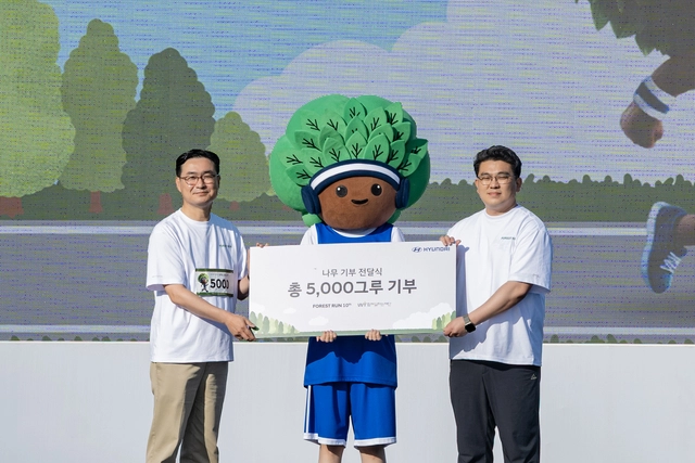 현대자동차의 친환경 사회공헌 캠페인 ‘포레스트런 2025’ 행사에서 정유석(왼쪽) 현대차 국내사업본부장(부사장), 이원태(오른쪽) 함께일하는재단 사무국장, ‘포레스트런’의 새로운 마스코트 ‘그루’(가운데)가 식재 기부 전달식 기념 촬영을 하고 있다. 현대차 제공.