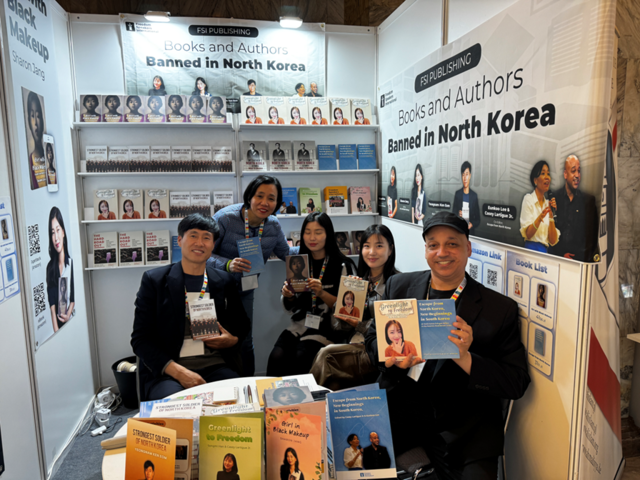 바르샤바 국제도서전에 참가한 탈북민 작가들과 FSI 관계자들이 부스에 앉아 출판한 책을 들어 보이고 있다. 왼쪽부터 엄영남 씨, 이은구 대표 , 장샤론 씨, 한송미 씨, 케이시 라티그 대표. FSI 제공