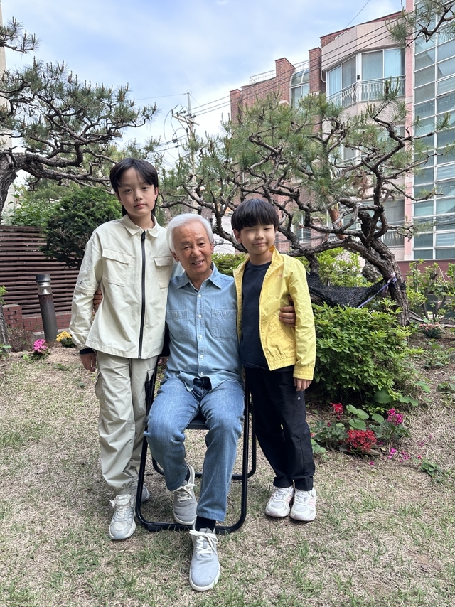 김홍신(가운데) 작가가 자택에서 두 손자와 함께 포즈를 취했다. 김 작가는 “손자들이 읽을 수 있는 책을 쓰고 싶었다”고 첫 동화책을 펴낸 이유를 설명했다.  김홍신문학관 제공