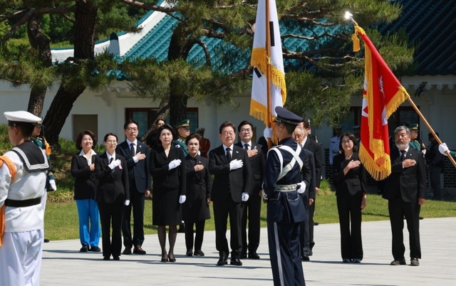이재명 대통령과 부인 김혜경 여사가 지난 4일 서울 동작구 국립서울현충원 현충탑 참배를 위해 들어서며 국기에 경례를 하고 있다.  뉴시스