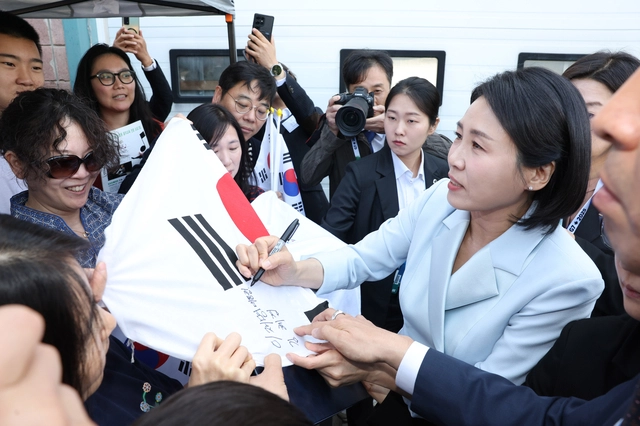 G7 정상회의에 참석하는 이재명 대통령과 함께 캐나다를 방문한 김혜경 여사가 17일(현지시간) 캘거리 한인회관에서 환영나온 주민들의 요청에 태극기에 서명하고 있다. 연합뉴스