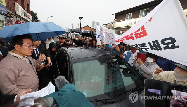 이재명 대통령이 더불어민주당 대선 후보 시절이던 지난 5월 제3차 골목골목 경청투어로 경북지역 방문에 나서 경북 고령군에서 대구에서 온 시민들의 지역주택조합 관련 하소연을 경청하고 있다. 연합뉴스