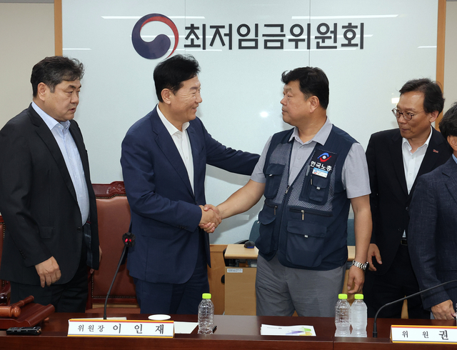최저임금위원회 사용자위원 운영위원인 류기정 한국경영자총협회 전무(왼쪽 두 번째)와 근로자위원 운영위원인 류기섭 한국노총 사무총장(오른쪽 두 번째)이 10일 정부세종청사에서 열린 제12차 전원회의에서 내년 최저임금을 시간당 1만320원으로 17년만에 합의로 결정한 뒤 악수하고 있다. 왼쪽은 이인재 위원장. 연합뉴스