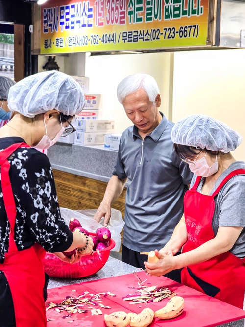 ‘불교와 여행을 사랑하는 사람들의 모임’ 봉사자들이 28일 짜장밥 조리를 위해 고구마 껍질을 벗기고 있다. 이수복 작가