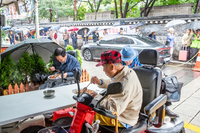 식사하기 위해 줄이 길게 늘어선 가운데, 어르신들이 원각사 무료급식소에서 지난 28일 식사하고 있다. 이수복 작가