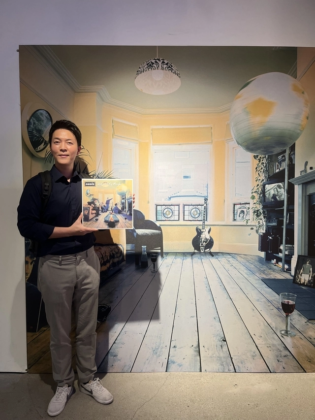 문화일보 안진용 기자가 오아시스의 데뷔 앨범 표지를 재현한 벽면을 배경으로 ‘인증샷’을 찍고 있다. 