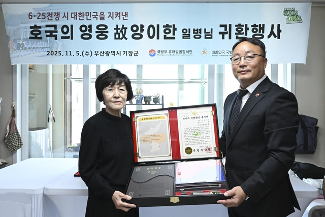 조해학(육군 중령·오른쪽) 국방부유해발굴감식단장 직무대리가 고 양이한 일병의 유가족 대표인 딸 양종금 씨에게 ‘호국의 얼 함’을 전달하고 있다. 국방부유해발굴감식단 제공