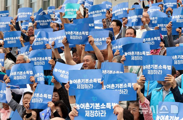 12일 오후 서울 여의도 국회 본청 앞 계단에서 열린 농어촌기본소득법 제정 촉구 기자회견에서 참가자들이 손피켓을 들고 구호를 외치고 있다. 사진 뉴시스.