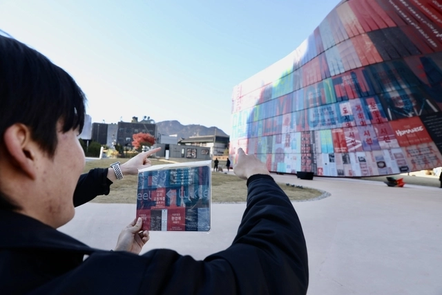 지난 17일 제5회 서울도시건축비엔날레 폐막식 현장에서 한 시민이 휴머나이즈 월에서 마우스패드에 인쇄된 부분을 찾아 기념사진을 찍고 있다. 동국제강그룹 제공