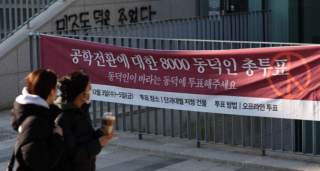 동덕여자대학교 공학 전환 타당성에 대한 외부 용역 결과 발표와 ‘공학 전환에 대한 8000 동덕인 의견 조사’ 학생 총투표가 실시되는 3일 서울 성북구 동덕여대에서 학생들이 총투표 관련 현수막 앞을 지나가고 있다. 뉴시스