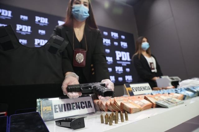중국 마피아 조직원으로부터 압수한 총기류 들어 보이는 칠레 수사관. X캡처·연합뉴스