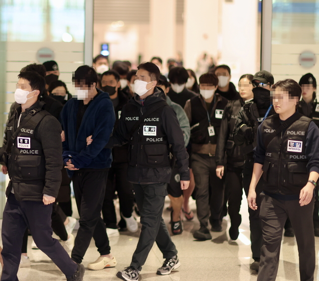 부산경찰청 수사관들이 캄보디아 현지에서 활동 중 검거된 사기 조직 피의자들을 인천공항을 통해 압송하고 있다. 부산경찰청 제공