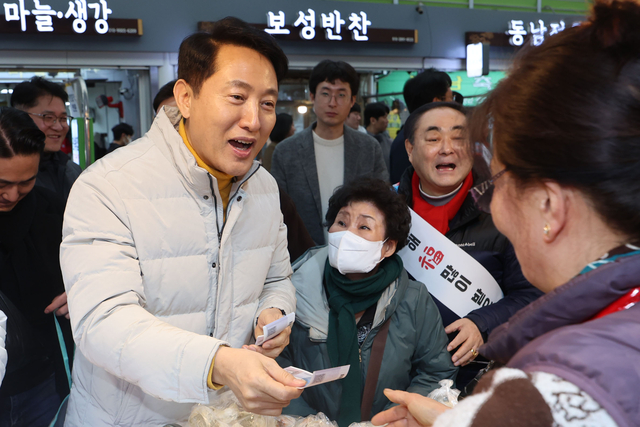 오세훈(왼쪽) 서울시장이 14일 서울 영등포구 영등포 전통시장을 방문해 설 명절 물가점검 겸  떡과 만두를 구매하고 있다. 뉴시스