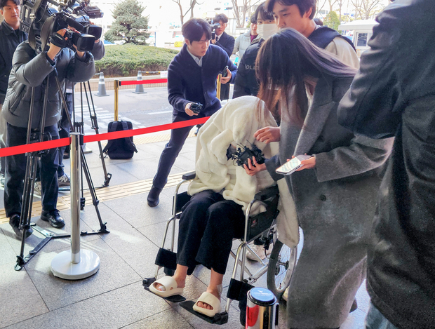 반포대교를 달리다 한강 둔치로 추락한 운전자 A 씨가 27일 서울 마포구 서부지방법원에서 열린 구속 전 피의자 심문(영장실질심사)에 옷으로 얼굴을 가리고 휠체어를 탄 채 출석하고 있다. 연합뉴스