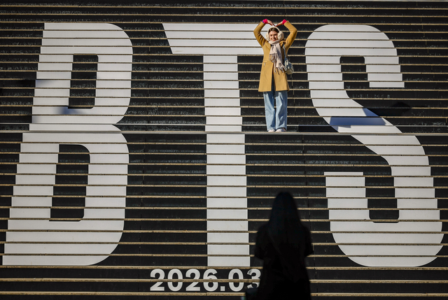 지난달 20일 서울 종로구 세종문화회관 계단을 찾은 외국인 여행객들이 방탄소년단(BTS) 래핑을 배경으로 사진을 찍고 있다. 뉴시스