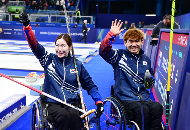 백혜진(왼쪽)과 이용석이 10일(한국시간) 이탈리아 코르티나 컬링 올림픽 스타디움에서 열린 2026 밀라노·코르티나동계패럴림픽 휠체어컬링 믹스더블 준결승에서 승리한 뒤 응원단을 향해 손을 흔들고 있다.  대한장애인체육회 제공 