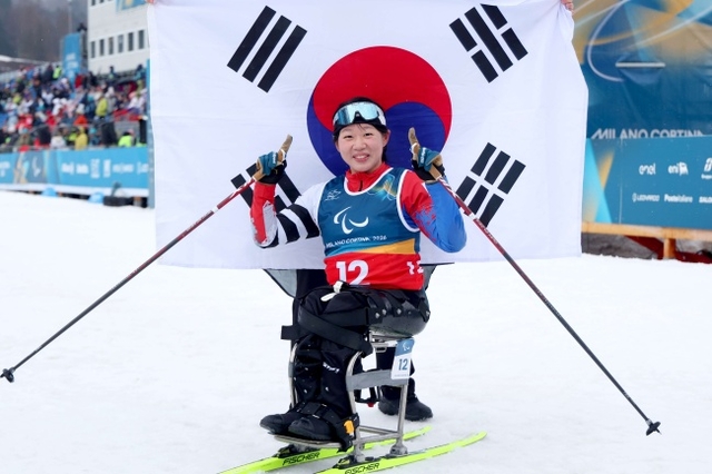 김윤지가 15일(한국시간) 이탈리아 테세로 크로스컨트리 스타디움에서 열린 2026 밀라노·코르티나동계패럴림픽 크로스컨트리스키 여자 20㎞ 인터벌 스타트 좌식에서 자신의 대회 두 번째 금메달을 확정한 뒤 태극기를 배경으로 기념 사진을 찍고 있다. 대한장애인체육회 제공