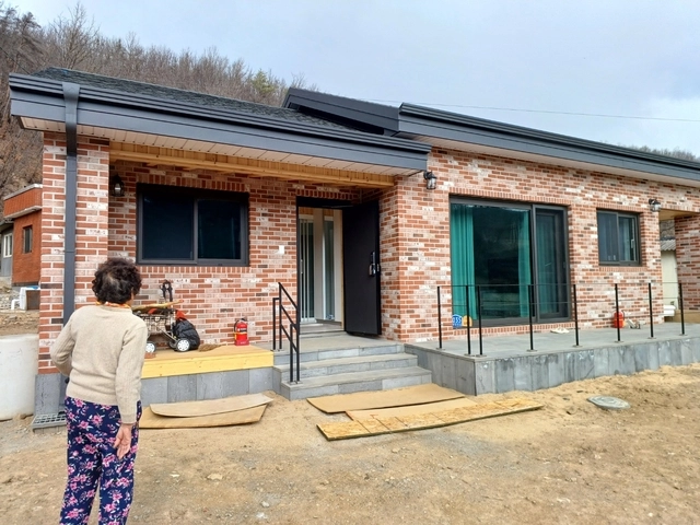 경북 안동시 일직면 원리 한 주민이 지난해 3월 경북 산불 피해로 불에 탄 집터에 새로 지은 주택을 바라보고 있다.