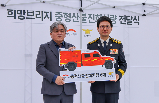 임채청(왼쪽) 희망브리지 전국재해구호협회 회장이 9일  24억 원 상당의 중형산불진화차량 6대와 산불진화용 등짐펌프를 기탁하며 김승룡 소방청장과 기념촬영을 하고 있다. 희망브리지 전국재해구호협회 제공