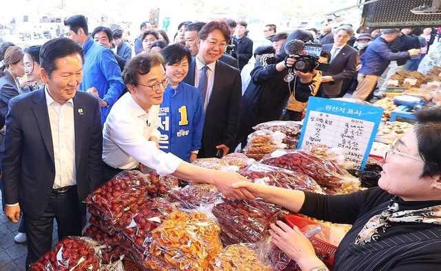 더불어민주당 정청래 대표와 전재수 부산시장 후보, 서은숙 부산진구청장 후보 등이 지난 15일 오후 부산 부산진구 부전시장을 돌며 상인들에게 인사하고 있다. 연합뉴스