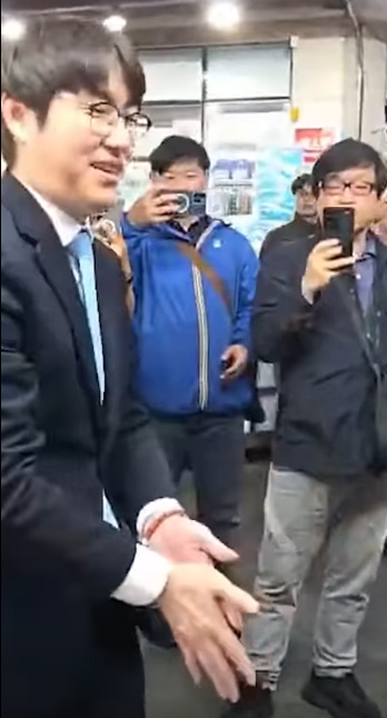 부산 북갑 국회의원 보궐선거에 더불어민주당 후보로 출마하는 하정우 전 청와대 AI미래기획수석이 29일 구포시장에서 상인과 악수한 뒤 손을 털고 있다.   박정훈 국민의힘 의원 페이스북 캡처