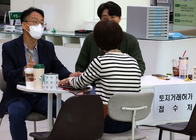 다주택자 양도 소득세 중과 면제 종료일인 9일 오후 서울 송파구청 1층 로비에 마련된 토지거래허가 접수처를 찾은 한 시민이 부동산정보과 담당자와 상담하고 있다. 뉴시스