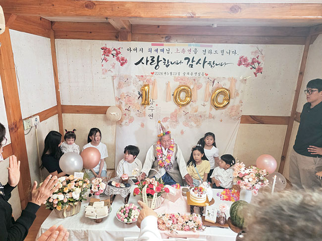 아버지가 100세 잔치에서 증손자들의 축하를 받고 있다.