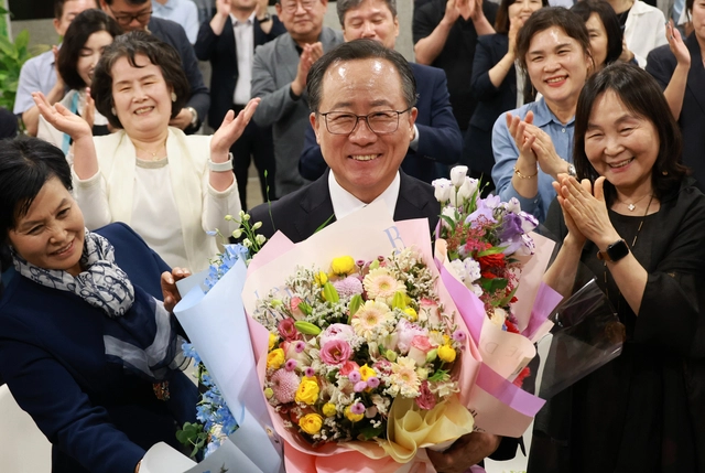 김석준(가운데) 부산시교육감 후보가 3일 밤 부산진구 선거사무소에서 당선이 확실시되자 꽃다발을 들고 환하게 웃고 있다.  연합뉴스