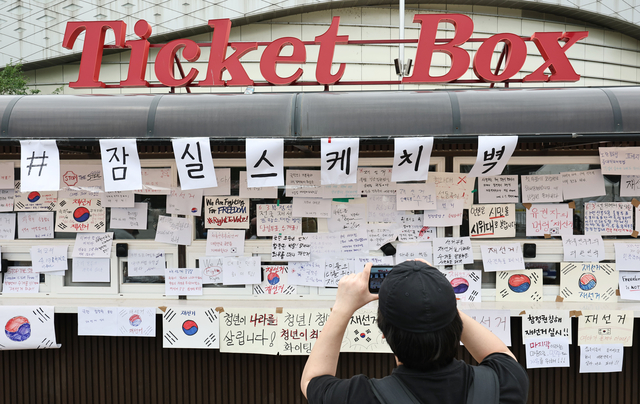 6·3 지방선거 투표지 부족 사태를 규탄하며 재선거를 요구하는 ‘잠실 개표소 봉쇄 시위’가 계속되고 있는 7일 서울 송파구 올림픽공원 핸드볼경기장 앞 매표소 부스에 재선거를 요구하는 문구 등이 적힌 종이가 붙어있다. 연합뉴스