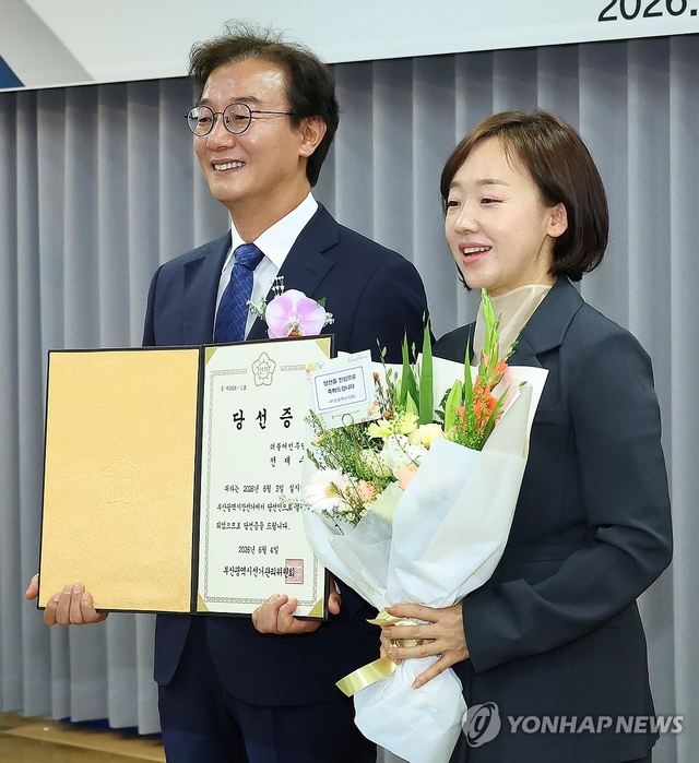 전재수 부산시장 당선인이 지난 5일 부산시선관위에서 열린 당선증 교부식에서 배우자 최혜진 씨와 함께 기념촬영을 하고 있다. 연합뉴스