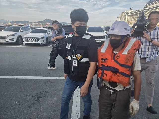 부산 오륙도 앞 바다에서 전복된 예인선 티엔에스캐처호에 타고 있던 인도네시아인 선원이 구조 이후 뭍에 도착한 뒤 해경의 안내를 받아서 부산해양경찰서로 향하고 있다.