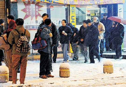 지난 26일 새벽 경기 성남시 태평1동 모란시장 인근 인력시장에서 일용직 근로자들이 진눈깨비 속에서 일감을 찾기 위해 서성이고 있다.