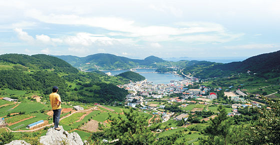 약과봉 북쪽 자락의 매바위(호랑바위)에서 내려다본 욕지도 항구의 모습. 욕지도는 외벽을 흰색으로 칠한 집들이 많은 데다 이즈음 섬 곳곳에 낭만적인 외양의 펜션들까지 속속 들어서 이국적인 분위기를 물씬 풍긴다.