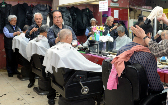 설을 앞둔 지난 15일 오후 서울 종로구 낙원동 뉴탑골이발관에서 이발사 권형규(왼쪽 세 번째) 씨가 손님의 머리카락을 정성스럽게 자르고 있다.  임정현 기자 theos@