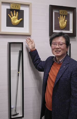 김길화 이사장이 8일 경남 김해의 롯데스카이 힐 김해골프장 클럽하우스 2층에 마련된 클럽챔피언 전시 코너 앞에서 자신의 핸드프린팅이 담긴 액자를 가리키고 있다.