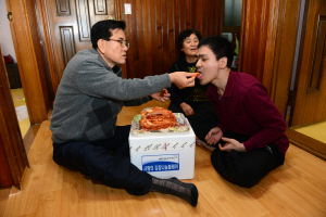 유덕열(왼쪽) 서울 동대문구청장이 최근 1대1 결연을 맺은 장애인가정을 방문해 장애인에게 김치를 먹여주고 있다. 동대문구 제공