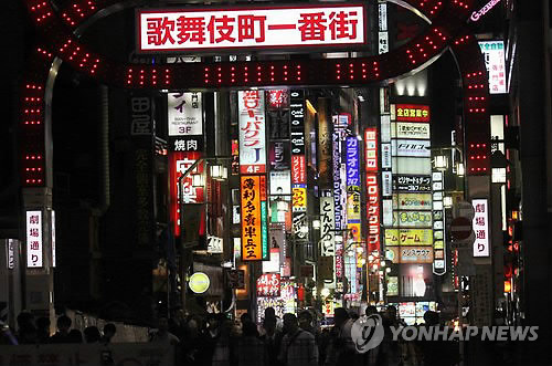 18일 오후 일본 도쿄도(東京都) 신주쿠(新宿)구 가부키초(歌舞伎町)의 유흥업소 밀집지구 입구의 횡단보도 앞에서 행인들이 녹색 신호를 기다리고 있다. ‘가부키초 일번가(一番街)’라고 쓰인 간판 뒤로 유흥업소가 불야성을 이루고 있다.