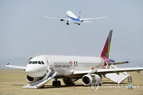 아시아나항공 여객기의 활주로 이탈 사고로 폐쇄돼 있다가 이착륙이 재개된 일본 히로시마(廣島)공항에서 17일 전일본공수(ANA) 항공기가 이륙하고 있다. 근처에 사고로 부서진 아시아나항공의 여객기가 놓여 있다. (히로시마 교도=연합뉴스)