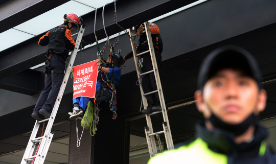 23일 오전 원자력안전위원회 회의가 열리고 있는 서울 종로구 세종로 KT 빌딩에서 소방관들이 신고리 원전 3호기의 사용 승인을 반대하면서 고공 시위를 벌이고 있는 국제환경운동 단체인 그린피스 회원을 보호하기 위해 안전줄을 설치하고 있다.