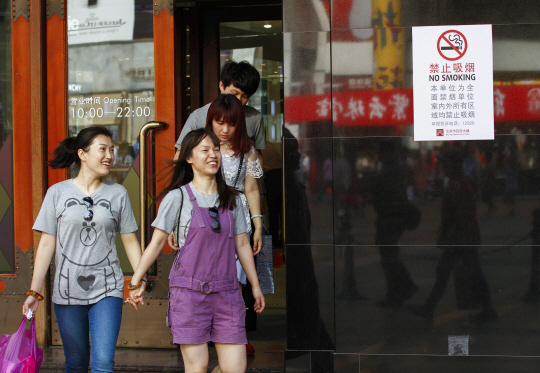 중국 정부가 5월 31일 세계 금연의 날을 맞아 1일부터 수도 베이징의 공공장소 등에서 강력한 흡연 규제 정책을 시행한 가운데 금연 표지판이 설치된 쇼핑몰에서 밝은 표정의 쇼핑객들이 걸어 나오고 있다.