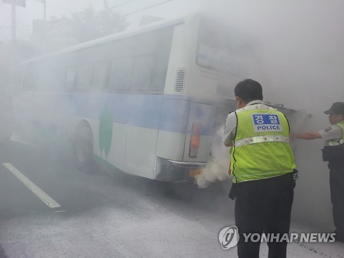 20일 오전 10시 45분께 부산 영도구 청학동 청학2동 주민센터 앞 도로를 운행 중이던 8번 시내버스 엔진에서 불이 나 연기가 치솟고 있다. 인근 청학지구대 경찰이 소화기로 불을 끄고 있다. (부산=연합뉴스)