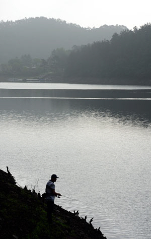 오랜 가뭄에도 불구하고 풍부한 수량을 유지하고 있는 초평호에서 낚시꾼이 이른 아침 낚시를 하고 있다.
