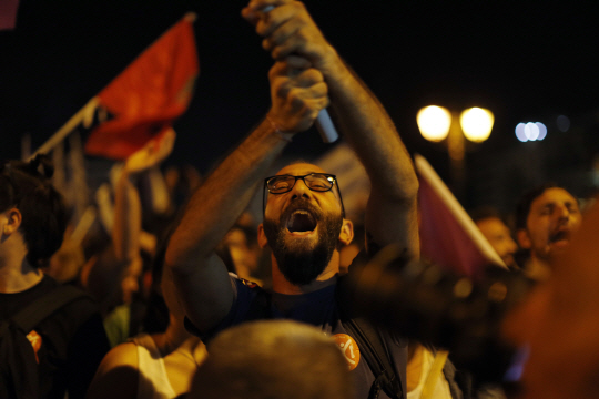 5일 치러진 그리스 국민투표에서 국제채권단의 추가긴축안에 대한 반대표가 61.33%로 압도적 다수로 나타나자 아테네 신타그마 광장에서 열린 긴축안 반대 지지집회에 참가한 한 남성이 깃발을 흔들며 환호하고 있다. AP연합뉴스