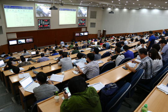 지난 14일 경기 광주 현대글로비스 ‘분당 중고차 경매장’에서 중고차 입찰에 참여한 매매업자들이 전광판에 뜬 차량 가격 등을 보며 차량 확보를 위한 응찰가를 고민하고 있다.
