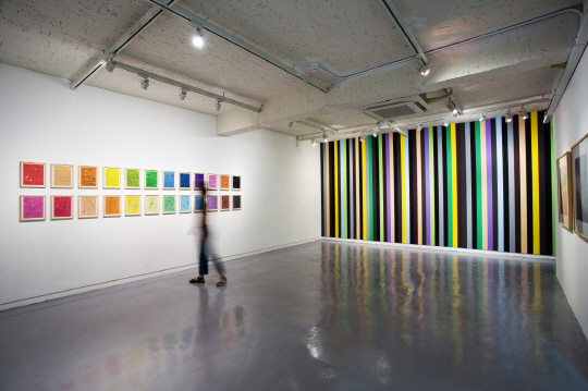 왼쪽 벽에는 색칠공부 도안 형태로 만들어진 박미나의 ‘12Colors Drawing Ⅲ, Ⅳ’(33×25.5㎝). 오른쪽 벽에는 사비나미술관의 정체성을 10개의 스트라이프 색채로 표현한 문형민의 ‘by numbers series’(785×703㎝, 2015) 작품이 각각 전시돼 있다.  사비나미술관 제공