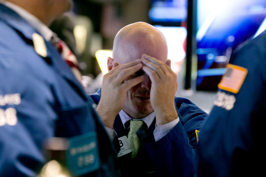 미국 뉴욕 증권거래소에서 한 거래인이 11일 중국의 갑작스러운 위안화 평가절하 충격으로 주가가 폭락하자 두 손으로 얼굴을 가리고 있다. 이날 다우존스산업평균지수는 전날보다 1.21% 떨어진 17402.84에 마감했다.