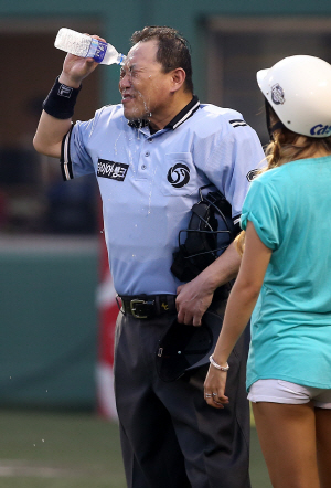 임채섭 심판이 지난 7월 30일 목동 구장에서 열린 프로야구 넥센-KT의 경기 도중 무더위를 달래기 위해 4회 초 생수를 얼굴에 붓고 있다.   문화일보 자료사진